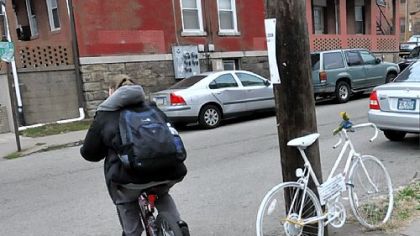 An unidentified cyclist passes a "ghost bike" at the corner of Meyran Avenue and Louisa Street in Oakland. It memorializes a father of two who was killed Aug. 6, 2009.
